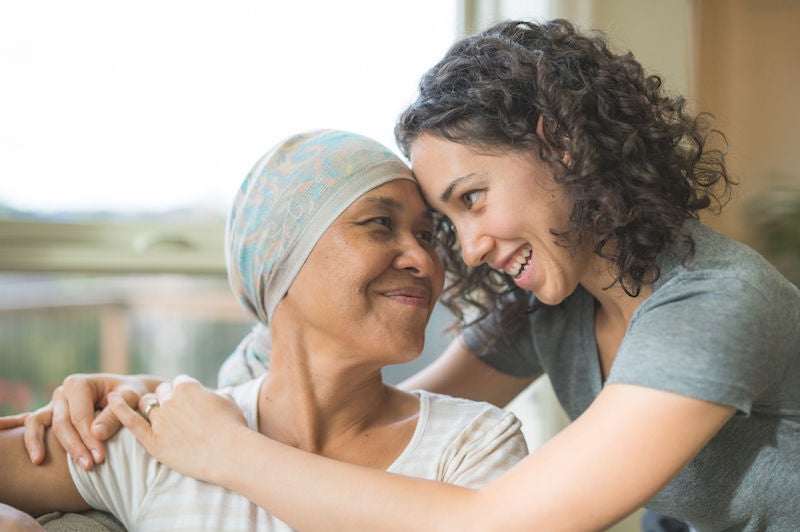 Ethnic adult female cancer patient hugging her daughter