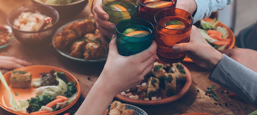 Cheers to us! Top view of people cheering with drinks while sitting at the rustic dining table