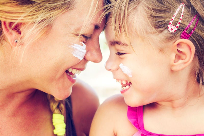 Shoot Planner Ref #107 - Beach lifestyle moments - Mother and daughter have a sunscreen on their cheeks and are smiling together. Genuine emotions, real mother of a child. AdobeRGB profile.